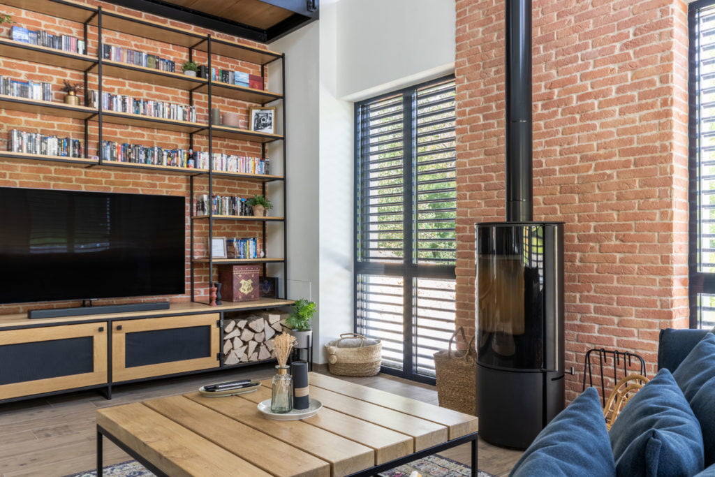 Living room with red brick wall in ORSOL stone behind TV cabinet and bookcase.