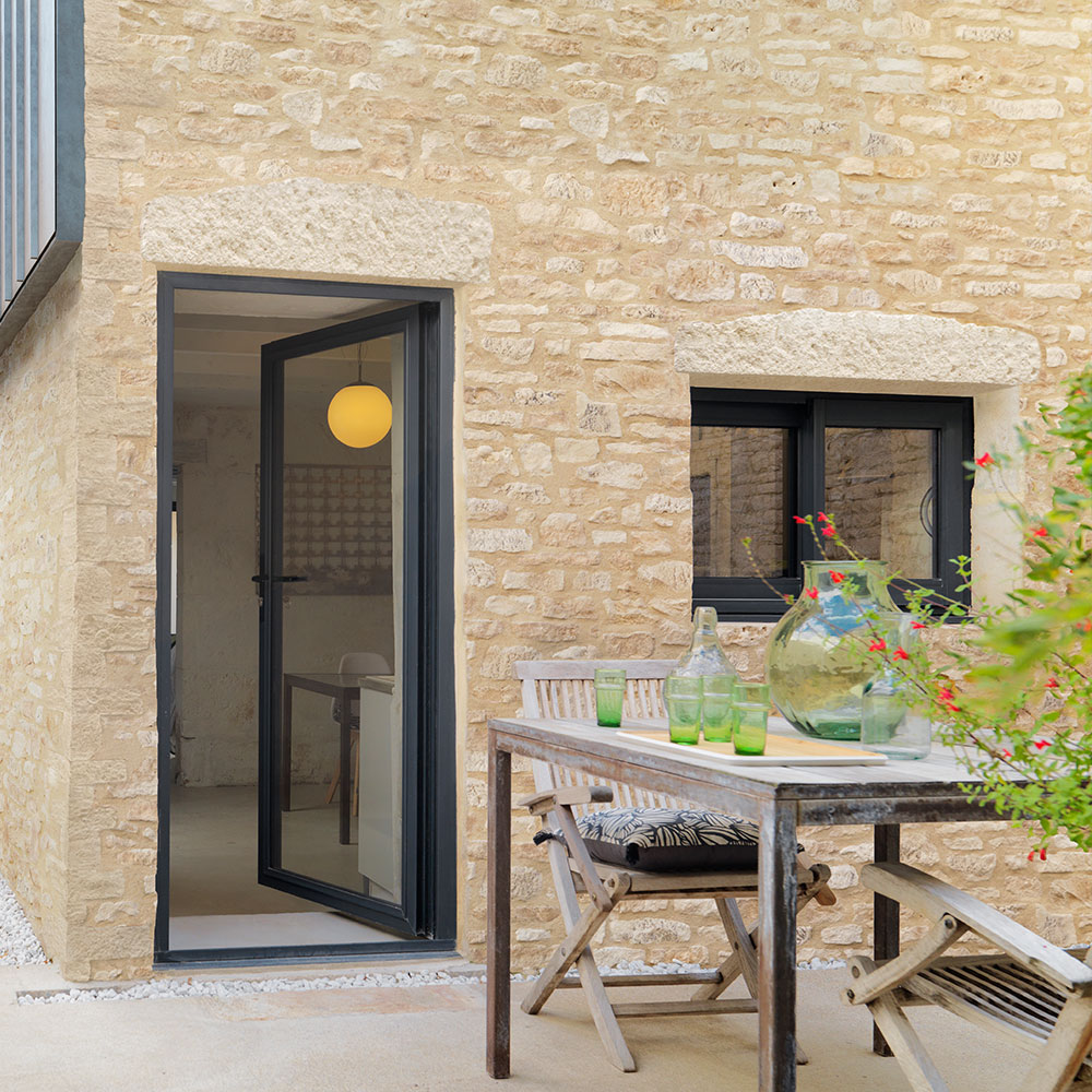 Façade extérieure en pierre de parement Causse ton naturel avec mobilier d’extérieur