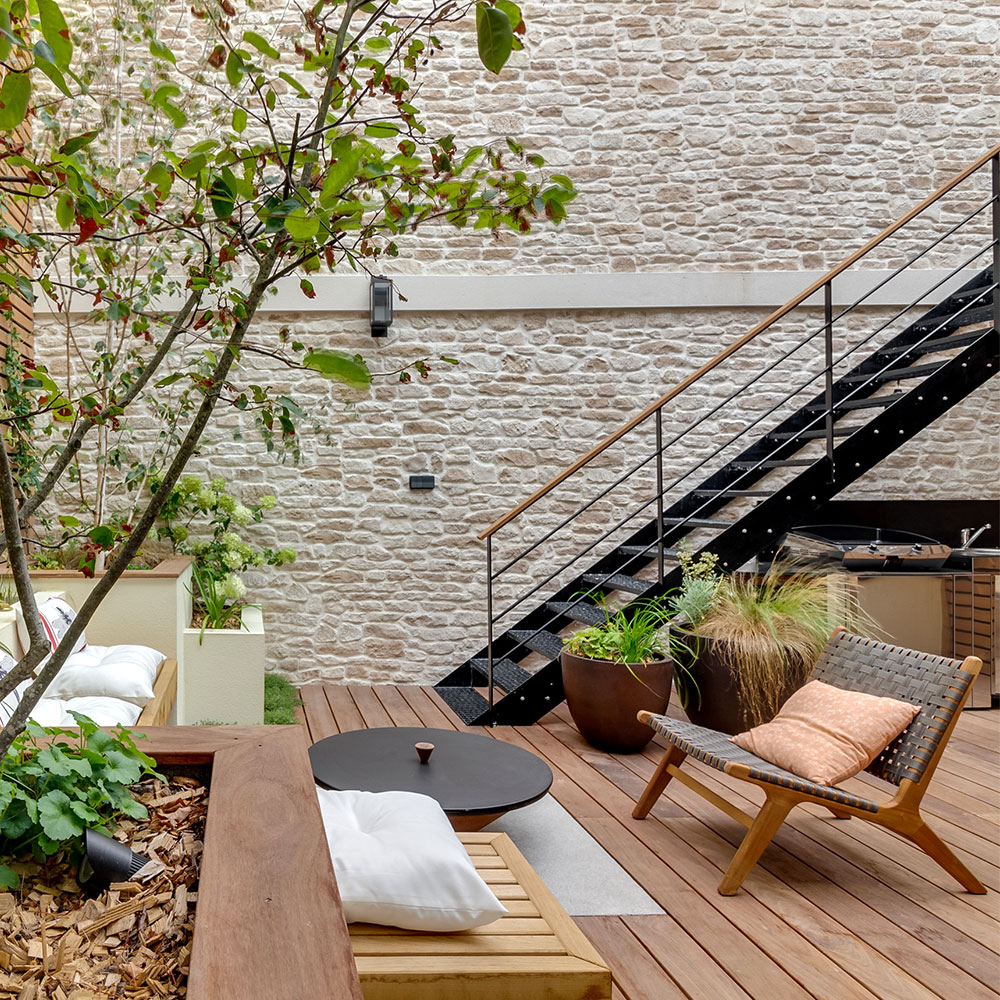 Terrasse extérieur en bois avec grand mur en parement Causse de chez ORSOL