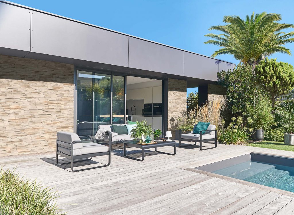 Maison d'architecte moderne ornée de parement GAIA avec terrasse en bois et piscine creusée
