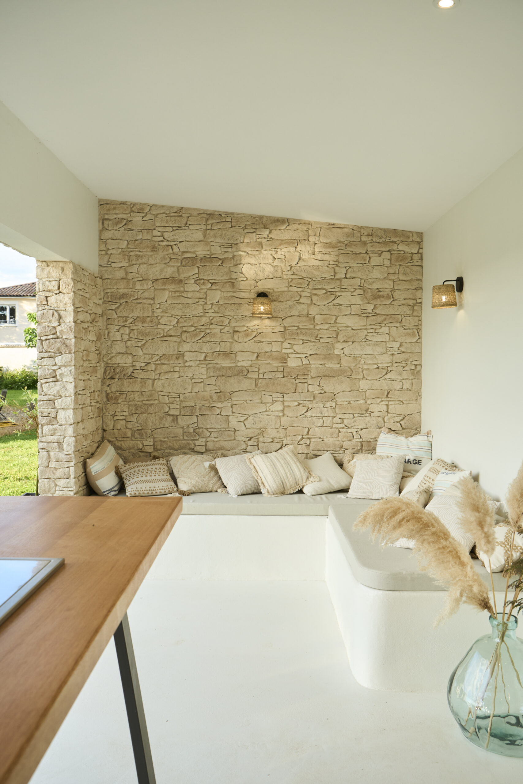 Una pool house spaziosa e inondata di luce, con una parete in pietra